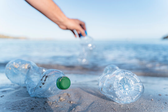 Hand collecting empty plastic bottles at seashore