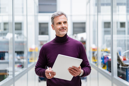 Mature businessman holding digital tablet in factory