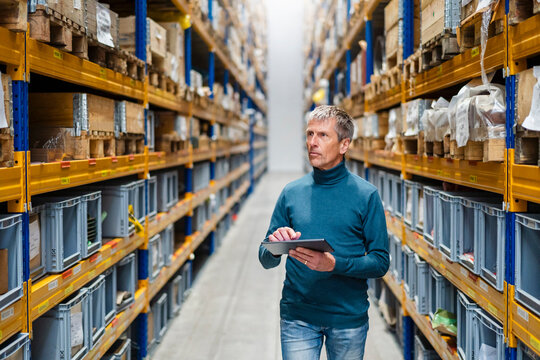 Businessman taking inventory holding tablet PC in warehouse