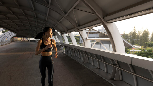 Smiling woman running on an urban bridge for morning fitness