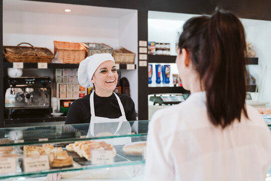 Happy female baker attending customer at bakery