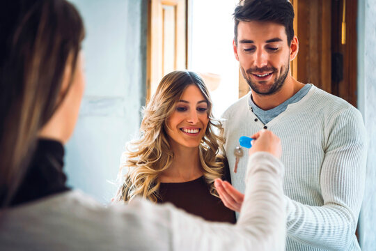 Estate agent handing over keys to happy young couple