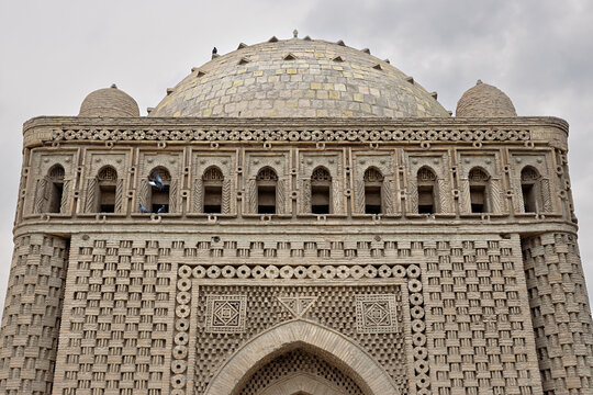 Ismail Samani Mausoleum in Bukhara featuring intricate geometric brickwork and a dome against an overcast sky. Historic Uzbekistan landmark ideal for travel publications and cultural heritage content.