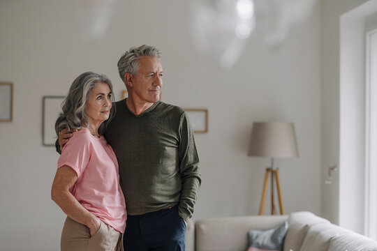 Senior couple standing in living room at home