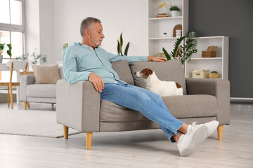 Fototapeta premium Mature man with cute Jack Russell terrier sitting on sofa at home