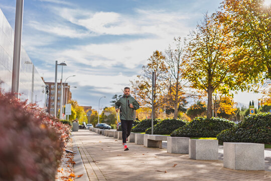 Person running on urban sidewalk during autumn street workout