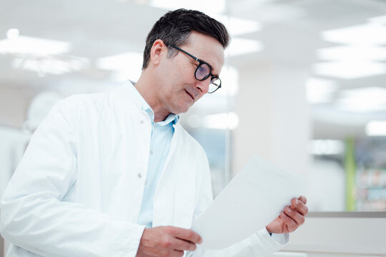 Man in lab coat analyzing medical reports in laboratory