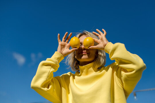 Mid adult woman covering eyes with lemon during sunny day