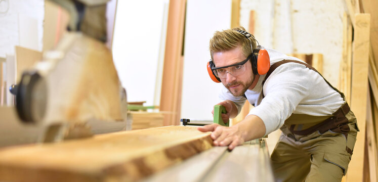 Carpenter using sawing machine in his workshop