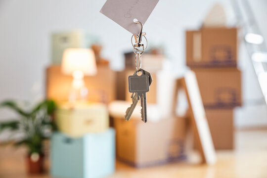 House key in front of cardboard boxes in an empty room in a new home