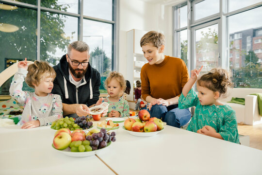 Children and teachers preparing fruit in kindergarten