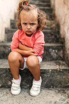 Portrait of little girl sitting on steps pouting mouth