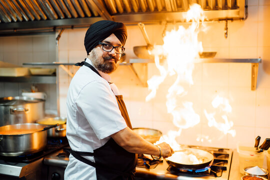 Indian chef flambing food in restaurant kitchen