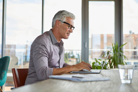 Mature man using laptop on table at home