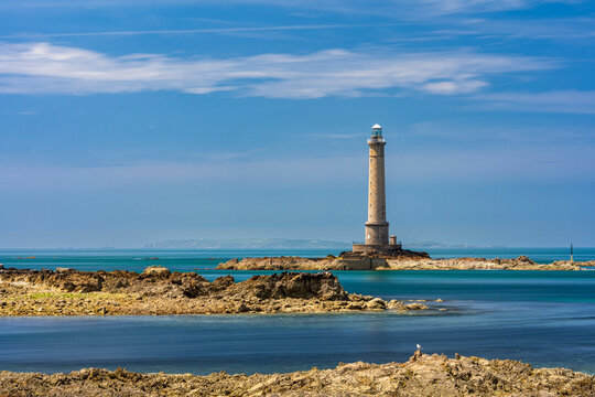 A stone lighthouse stands on a rocky coast in Normandy France