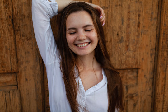 A smiling female leans against an old door in the summer rain