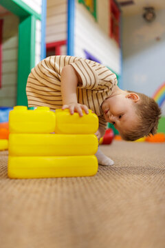 Focused toddler child stacking big construction bricks at kids club