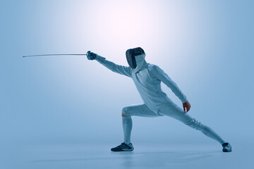 Fototapeta premium Male fencer performing powerful attacking lunge with epee in modern studio. Concept of competitive fencing, precision movement, tactical attack, athletic discipline, and individual performance.