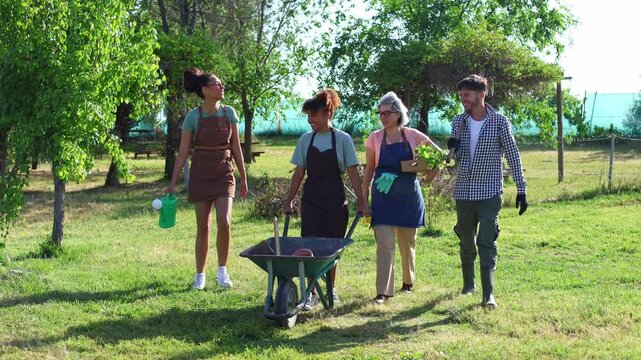 Multiethnic group of gardeners walking with wheelbarrow