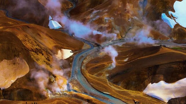 A mesmerizing, high-altitude tracking shot following the course of a steaming thermal stream as it cuts through vibrant, geologically active rhyolite slopes.