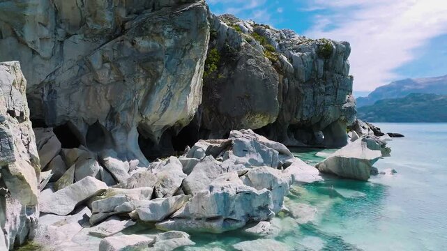 A smooth, immersive aerial glide navigating the intricate, swirling patterns of the Cuevas de M&aacute;rmol against vibrant glacial lake water.