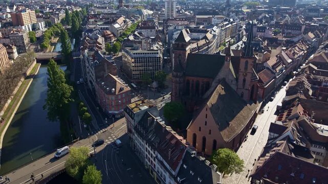 Saint Peter the Old Protestant Church overlooks the Faux Rempart Canal beside Stone Gate Bridge in Strasbourg, Bas-Rhin, Grand Est, France, within the UNESCO-listed Grande &Icirc;le, drone lateral slide.