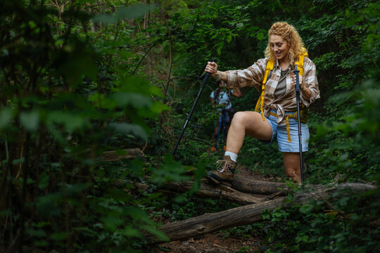 Woman hiking forest trail using trekking poles