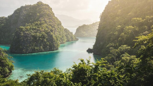 Dramatic limestone karst islands frame a stunning turquoise channel bathed in warm golden sunlight, showcasing an awe-inspiring seascape perfect for expedition cruise advertising and sustainable trave