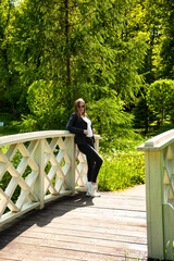 Fototapeta premium Sunlit Bridge Moment With a Stylish Woman Enjoying Nature's Embrace in a Vibrant Outdoor Setting