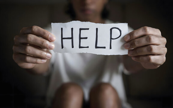 A person holding a torn piece of white paper with the word help written in black marker, expressing a need for support, mental health awareness