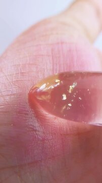Trying to apply pink lip balm on palm. Extreme close up showing hand starting to turn reddish after application. Lip care product texture for beauty concept.