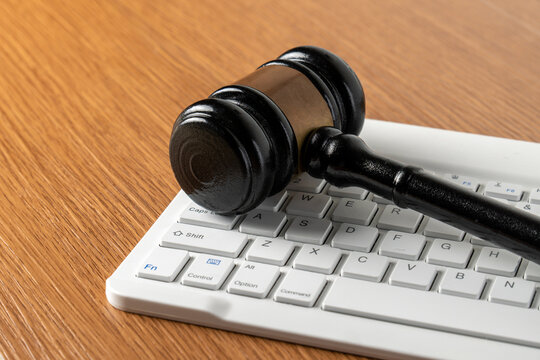Wooden judge gavel on a white computer keyboard. Cyber law, digital justice, online crime, internet regulations concept.