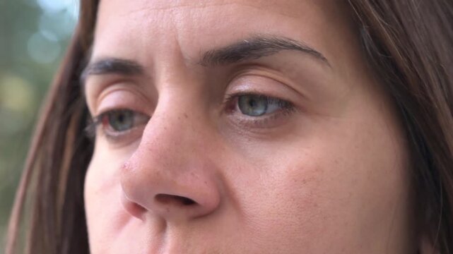 Extreme close up of a woman's focused face and eyes while reading outdoors
