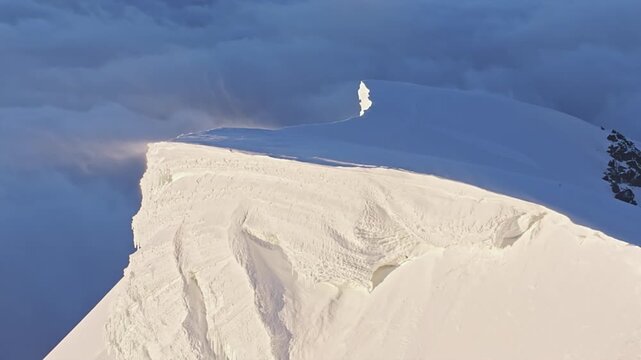 Large piece of snow and ice breaking off a mountain ridge, causing a small avalanche
