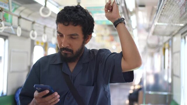 Asian Man Standing and Using Smartphone Inside Commuter Train Indonesia