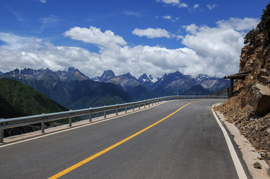 Scenic mountain road under blue sky with white clouds