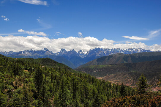 Breathtaking mountain range with lush green forests under clear blue sky