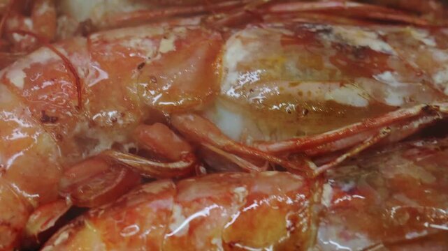 Close up of fresh seafood preparation. Shrimps or prawns are frying in a pan, and their shells are turning a vibrant orange color