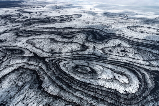 Vatnajokull National Park in Iceland, showcasing striking black volcanic ash patterns and crevasses, Iceland
