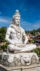 Fototapeta premium White marble statue of deity meditating on a lion's head base, symbolizing divine peace and strength, ideal for spiritual or cultural representation.