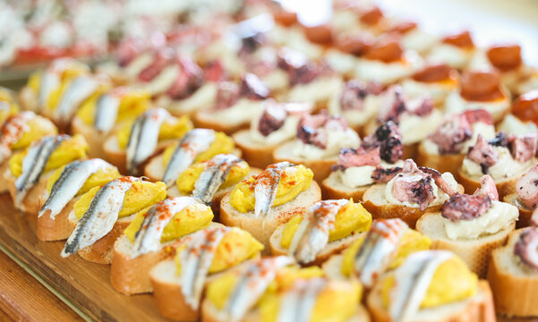 Fava pur&eacute;e topped with seafood and herbs, including anchovy and octopus, a classic colorful Santorini meze served on crisp bread with bright Mediterranean flavors.