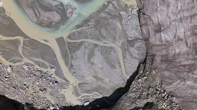 A cinematic topdown perspective showing the effects of climate change on the Morteratsch glacier, featuring melting ice and sedimentrich rivers in the Swiss Alps.