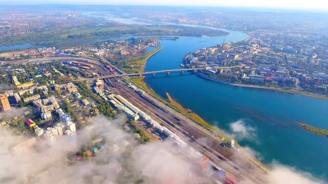 Amazing aerial flight over the city, flying through morning fog above a river and bridge