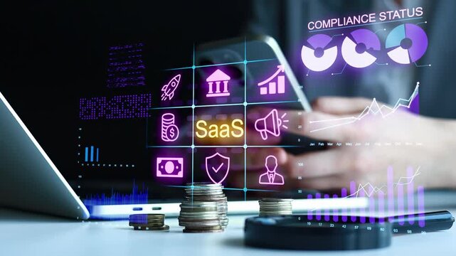Business professional uses smartphone to access SaaS tools with graphs and stats displayed on screen in office setting.