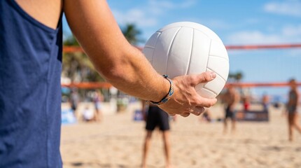 Fototapeta premium Person holding volleyball on sunny beach with players in background