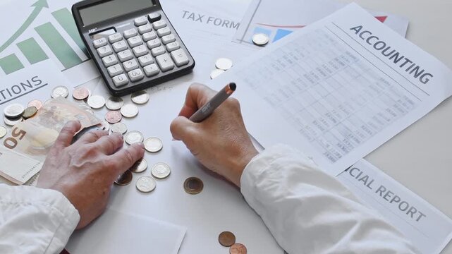 A man reviews tax returns, accounting documents, and schedules, writing a plan