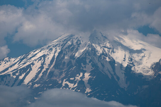 Majestic snow peak of mount Ararat in clouds with blue sky copy space