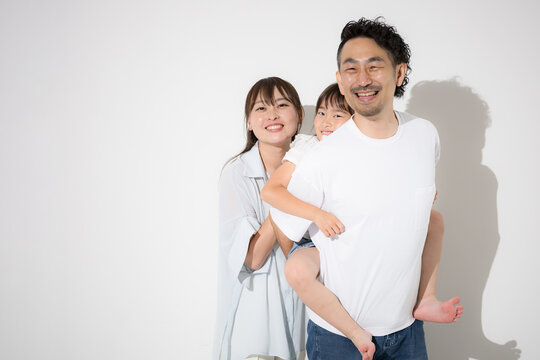 A close-knit family smiling against a white background&mdash;happy family life and a healthy lifestyle. Insurance, NISA, education, short-sleeved summer attire, looking directly at the camera.