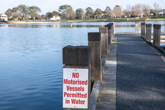 A public advisory sign reading "NO Motorised Vessels Permitted in Water"on a post along a lakeside jetty in Point Cook, suburb of Melbourne, Victoria, Australia.