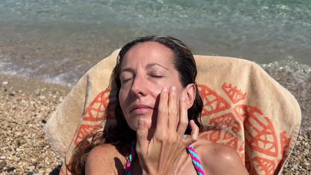 &Oacute;rbita de mujer aplicando crema solar en la cara